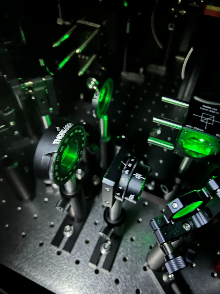Laser optics table with precision Thorlabs kinematic mounts and green laser beam paths